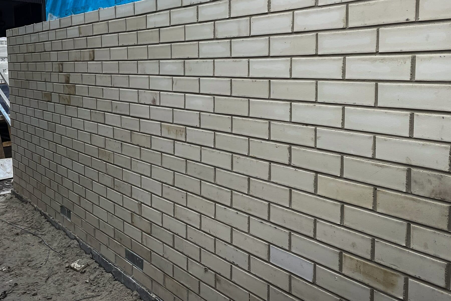 Raking view along a freshly laid cream face brick wall